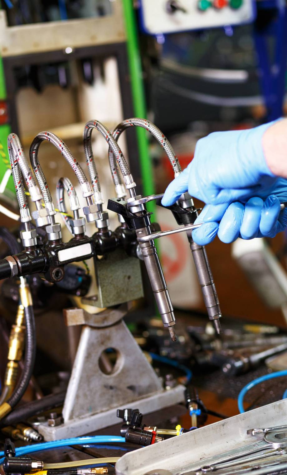 Professional mechanic testing diesel injector in his workshop.